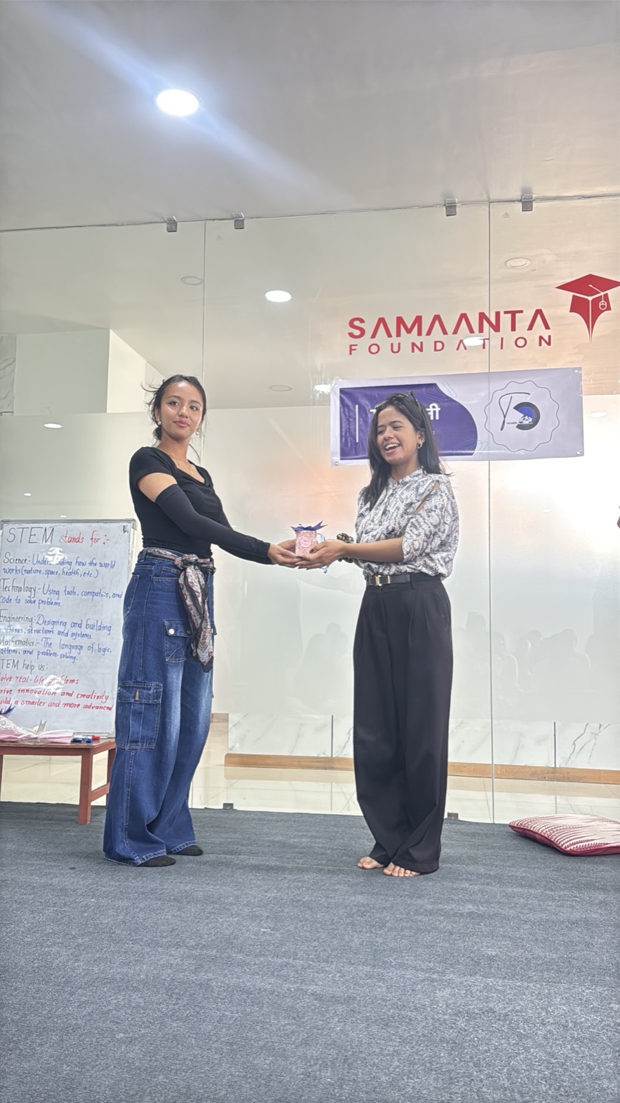 Labbi receiving a token of love from a Tech Toli organizer in front of the Samaanta Foundation banner