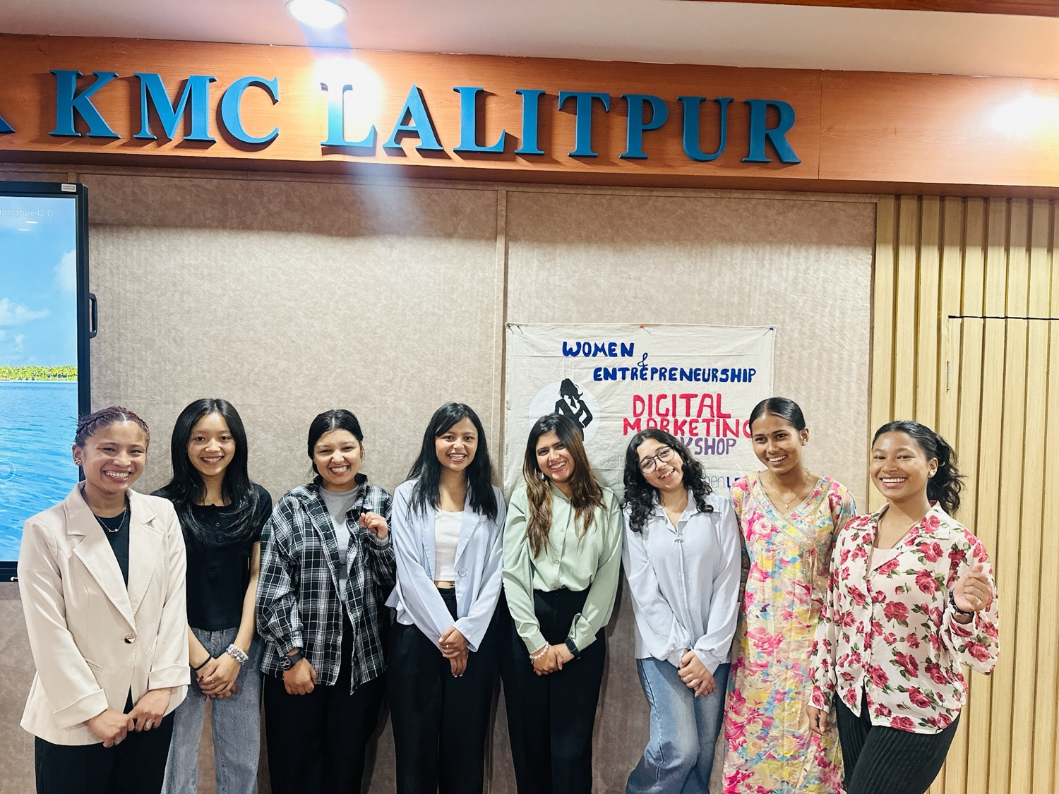 Management students with the Digital Kala facilitators at the Women Entrepreneurship Digital Marketing Workshop, in front of the KMC Lalitpur sign